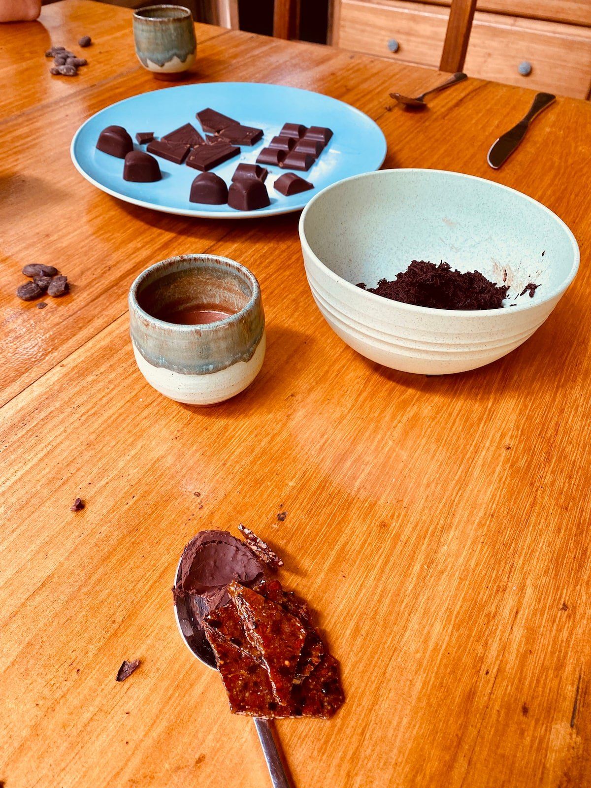 Moulded chocolates and a bowl of ground cacao on a workshop table