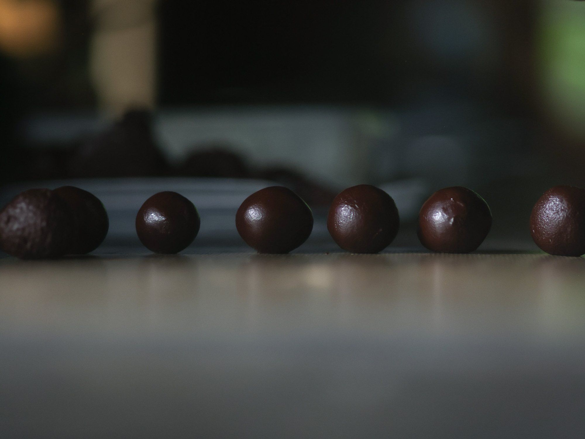 A row of finished chocolates on a dark table